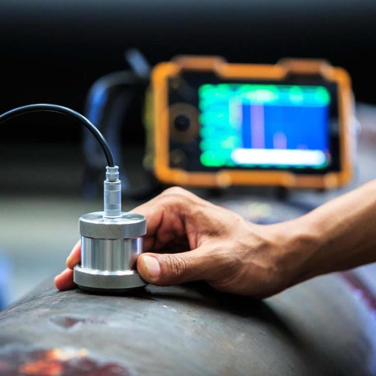 Ultraschallprüfung Ein Techniker misst mit einem Sensor die Oberfläche eines Rohres. Im Hintergrund ein Messgerät. Ultraschallprüfung